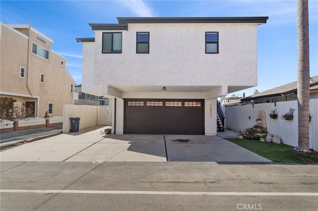 view of front of home with fence, driveway, an attached garage, stucco siding, and stairs