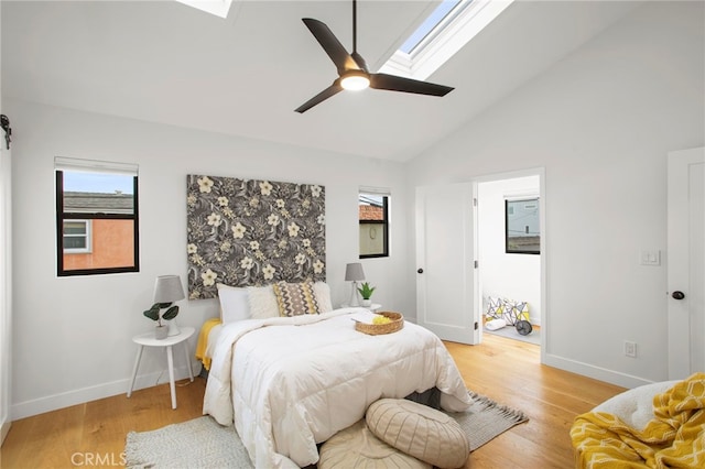 bedroom with light wood finished floors, vaulted ceiling with skylight, and baseboards