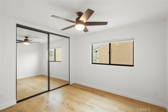 unfurnished bedroom featuring a closet, ceiling fan, baseboards, and wood finished floors