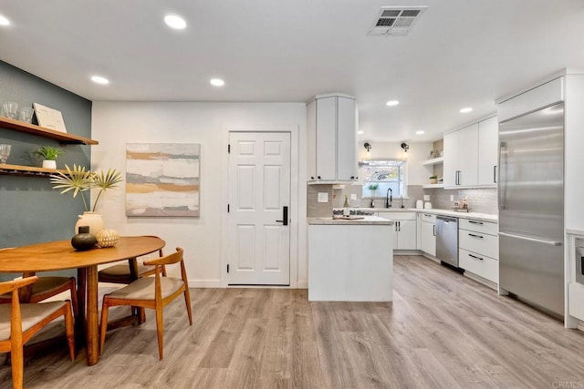 kitchen with visible vents, open shelves, light countertops, stainless steel appliances, and a sink