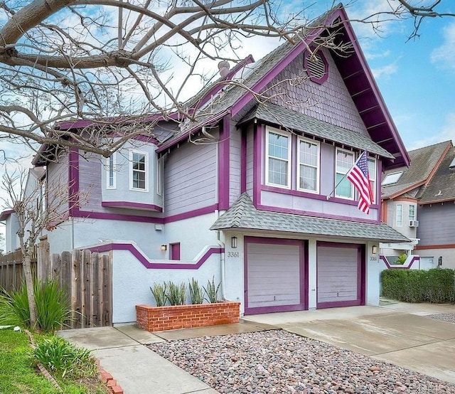 victorian house with fence, driveway, roof with shingles, stucco siding, and a garage