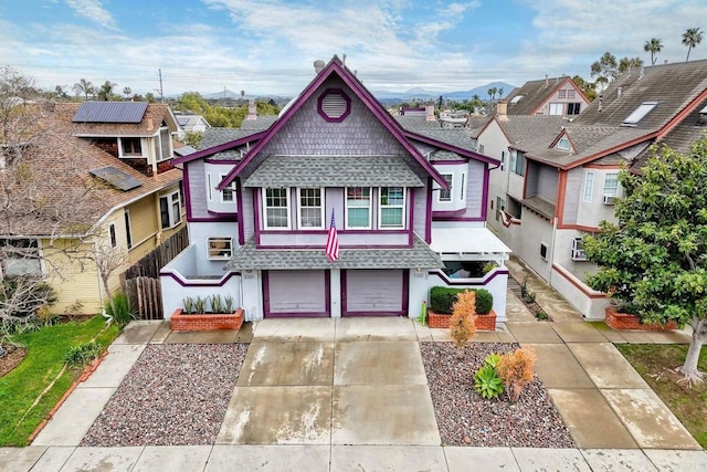 victorian home featuring an attached garage, fence, driveway, and a shingled roof