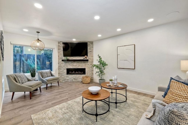 living area featuring recessed lighting, light wood-type flooring, baseboards, and a fireplace