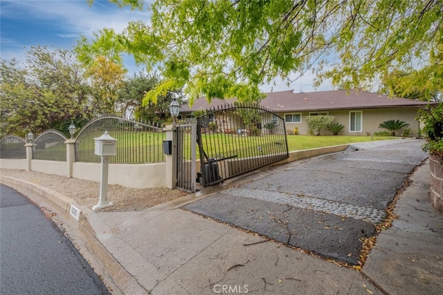 ranch-style house with a front lawn, a gate, a fenced front yard, and stucco siding