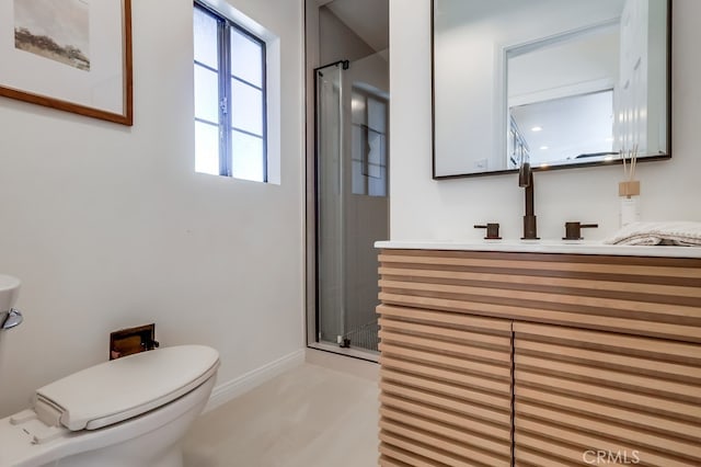 bathroom featuring vanity, toilet, baseboards, and a stall shower