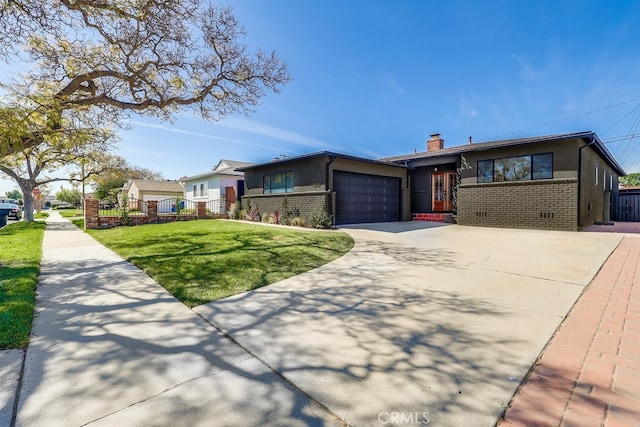 view of front facade with a chimney, concrete driveway, a front lawn, a garage, and brick siding