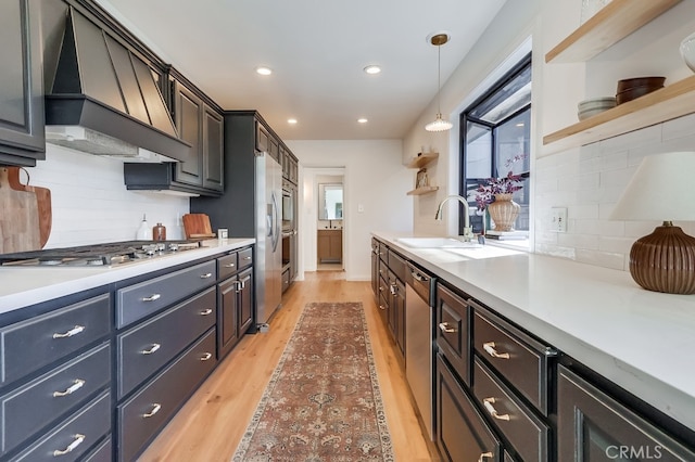 kitchen with open shelves, a sink, custom range hood, light wood-style floors, and appliances with stainless steel finishes