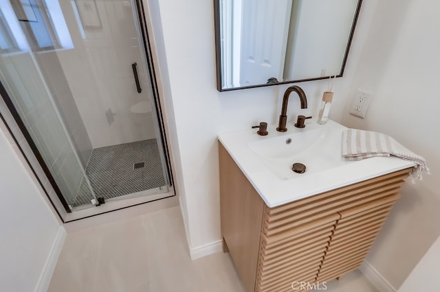 bathroom featuring vanity, a shower stall, and baseboards