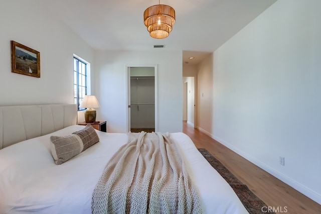 bedroom featuring wood finished floors, visible vents, baseboards, a closet, and a walk in closet