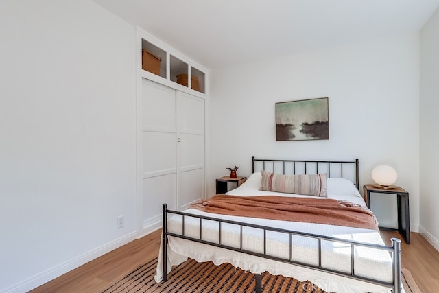 bedroom with a closet, baseboards, and light wood-style floors