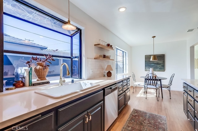 kitchen featuring light wood finished floors, visible vents, light countertops, stainless steel dishwasher, and a sink