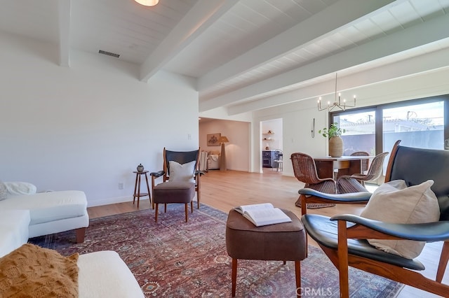 living room featuring wood finished floors, baseboards, visible vents, an inviting chandelier, and beam ceiling