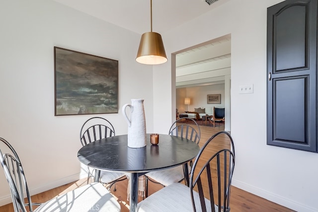 dining area with visible vents, baseboards, and wood finished floors