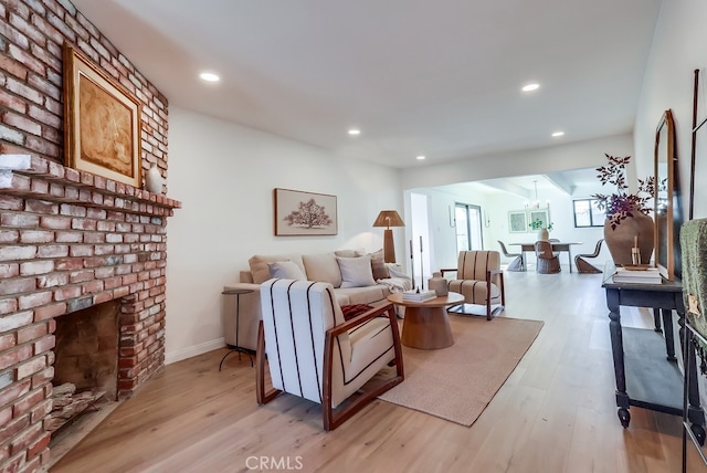 living area with baseboards, a fireplace, recessed lighting, light wood-style floors, and a chandelier