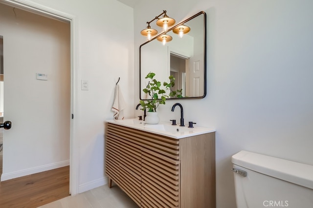 bathroom featuring a sink, baseboards, toilet, and double vanity