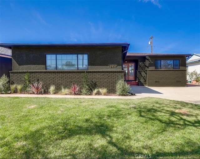 ranch-style home with stucco siding, brick siding, and a front lawn