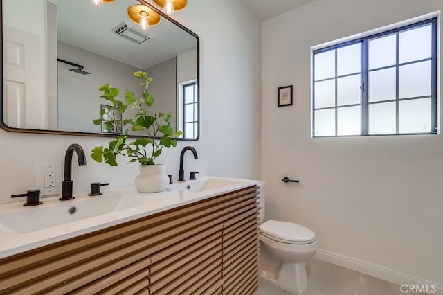 bathroom featuring a sink, visible vents, toilet, and a healthy amount of sunlight