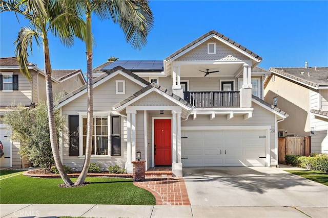 view of front of property featuring a balcony, a ceiling fan, driveway, a garage, and roof mounted solar panels