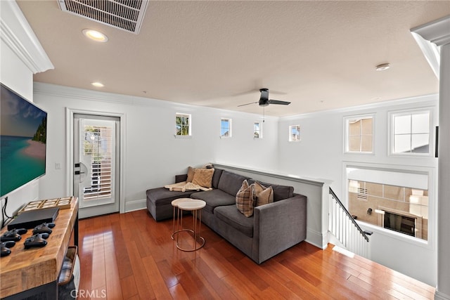 living room featuring visible vents, ornamental molding, a textured ceiling, hardwood / wood-style floors, and recessed lighting