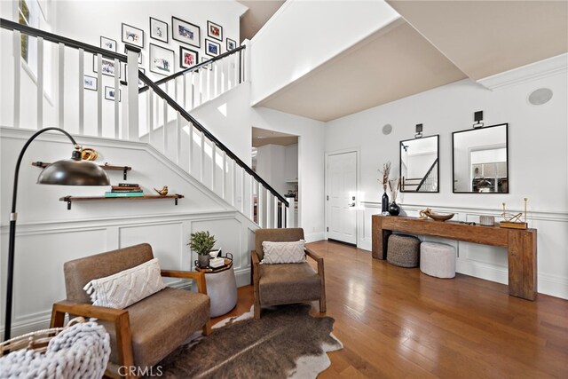 living area featuring stairs, a decorative wall, and wood finished floors