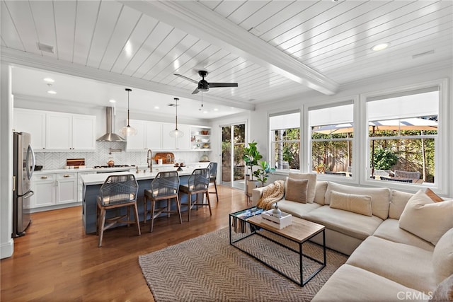 living room featuring recessed lighting, beamed ceiling, crown molding, and light wood finished floors