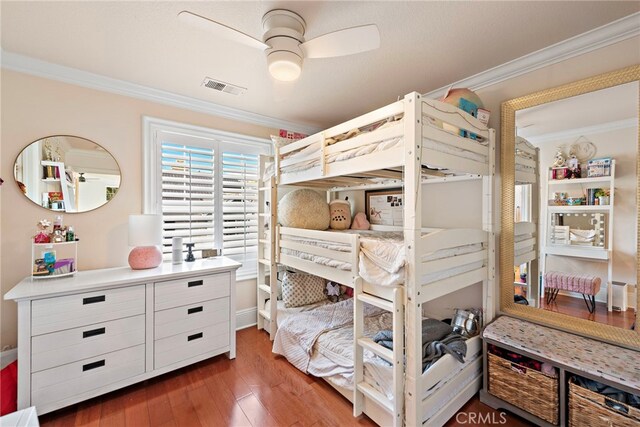 bedroom with ceiling fan, visible vents, wood finished floors, and crown molding