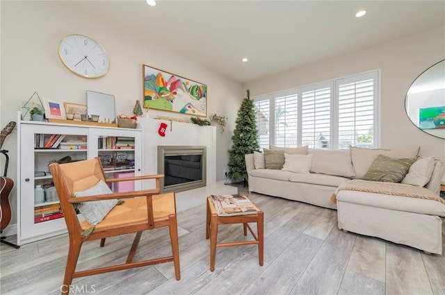 living room with a glass covered fireplace, recessed lighting, and wood finished floors