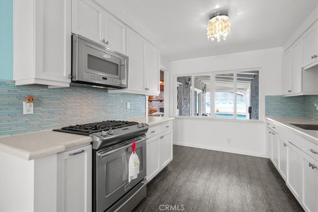 kitchen with backsplash, light countertops, appliances with stainless steel finishes, white cabinetry, and dark wood-style flooring