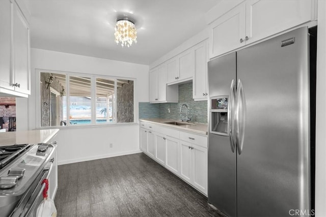 kitchen with a sink, white cabinetry, stainless steel appliances, light countertops, and decorative backsplash