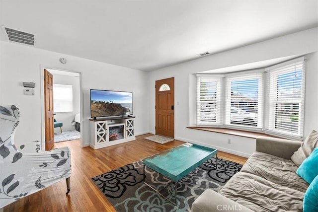 living room with visible vents, baseboards, and wood finished floors