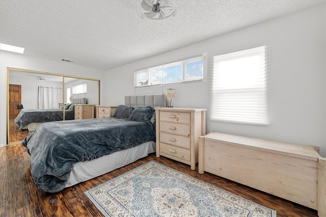 bedroom featuring visible vents, a textured ceiling, a closet, and wood finished floors