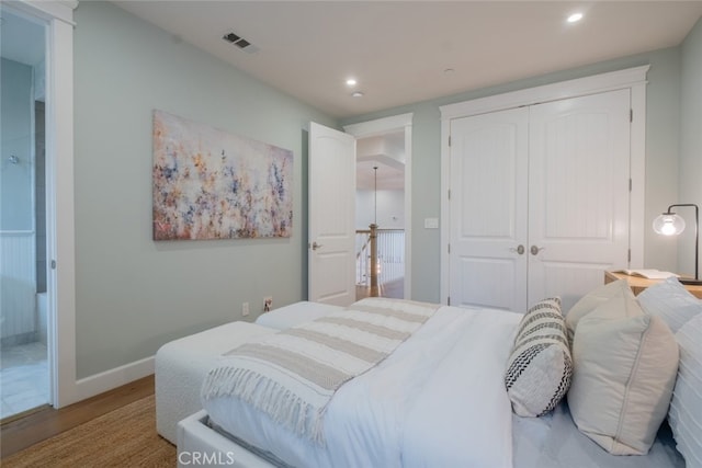 bedroom with a closet, visible vents, recessed lighting, and wood finished floors