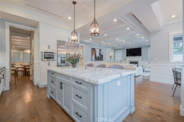 kitchen with white cabinets, a fireplace, stainless steel built in fridge, and hardwood / wood-style floors