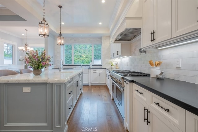 kitchen featuring a chandelier, custom exhaust hood, ornamental molding, white cabinetry, and range with two ovens