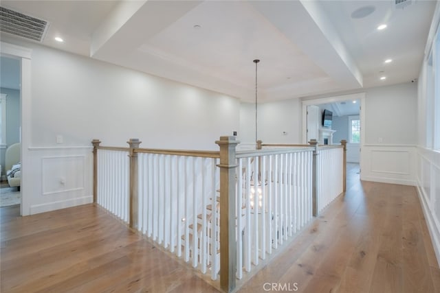 hallway featuring visible vents, a wainscoted wall, recessed lighting, hardwood / wood-style flooring, and a decorative wall