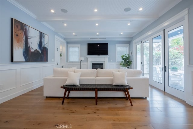 living area featuring a glass covered fireplace, a decorative wall, light wood-style floors, and beamed ceiling