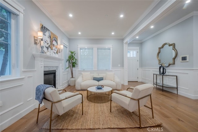 living room featuring a premium fireplace, ornamental molding, recessed lighting, wood finished floors, and a decorative wall