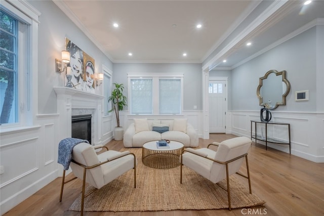 living area featuring a fireplace, wood finished floors, a decorative wall, ornamental molding, and recessed lighting
