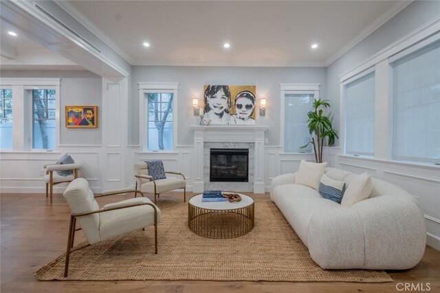 sitting room featuring a decorative wall, crown molding, a premium fireplace, and wood finished floors