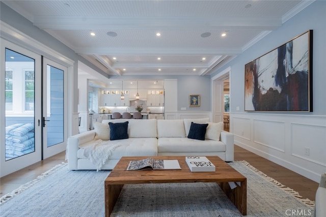 living room featuring beamed ceiling, light wood-style flooring, recessed lighting, french doors, and a decorative wall