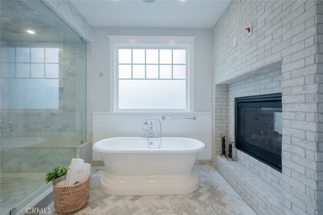 bathroom featuring a soaking tub, a wainscoted wall, a shower, and a brick fireplace