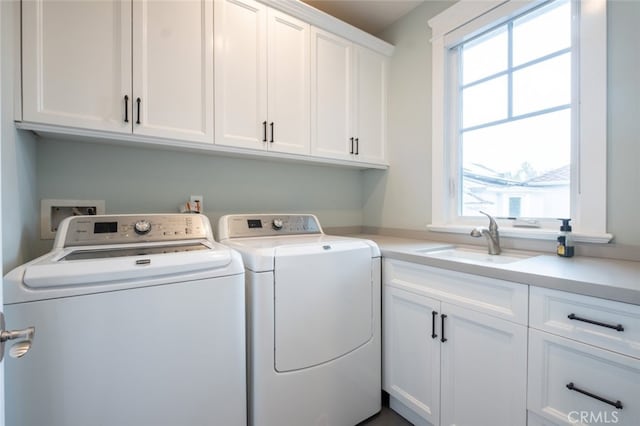 laundry room with washing machine and dryer, cabinet space, and a sink