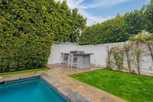 view of pool with outdoor dry bar, a fenced in pool, a lawn, a fenced backyard, and a patio area