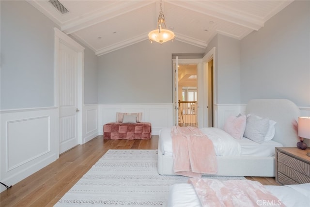 bedroom featuring wood finished floors, visible vents, lofted ceiling with beams, wainscoting, and wooden ceiling