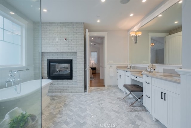 full bath with a sink, recessed lighting, double vanity, a soaking tub, and a brick fireplace