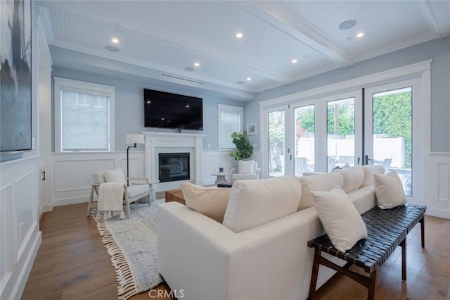 living room featuring french doors, wood finished floors, beam ceiling, and a decorative wall