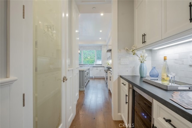 bar with tasteful backsplash, wine cooler, recessed lighting, stainless steel stove, and wood finished floors