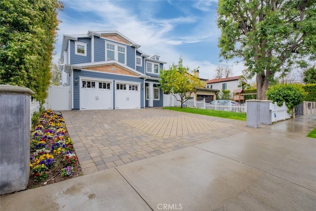 view of front of property featuring decorative driveway, fence, and an attached garage