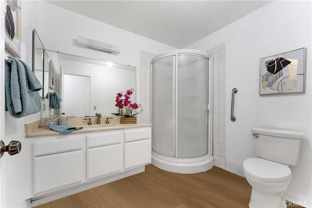 full bath featuring a stall shower, toilet, wood finished floors, and vanity