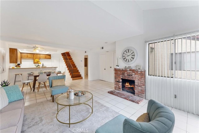 living area featuring light tile patterned floors, stairway, ceiling fan, and a fireplace